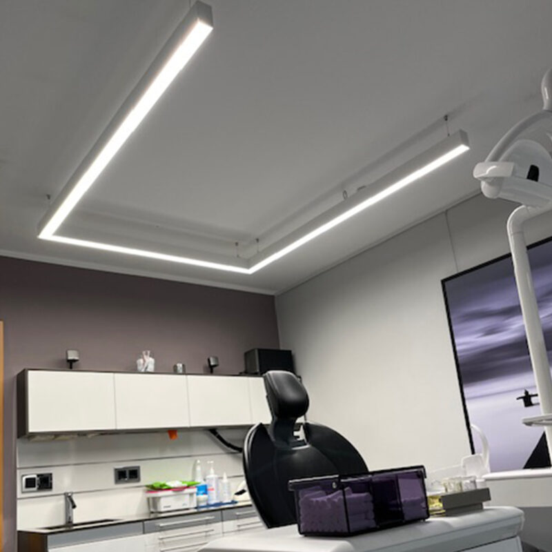 La lampe PHU White en forme de U à spectre complet de DentLed, installée dans une salle de soins moderne d'une clinique dentaire à Melle, permet un travail dentaire de précision.