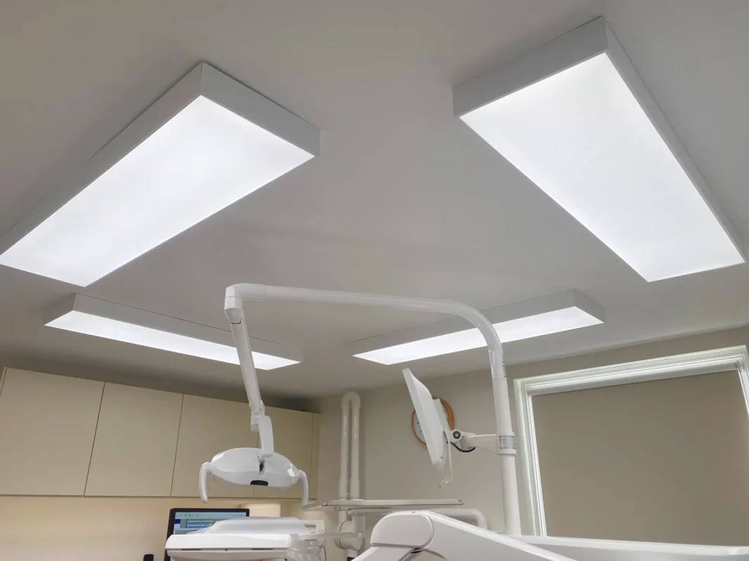 Quatre panneaux LED de plafond DentLED DL120 à spectre complet, installés dans des cadres en saillie autour du fauteuil dentaire chez Priory Dental Care.